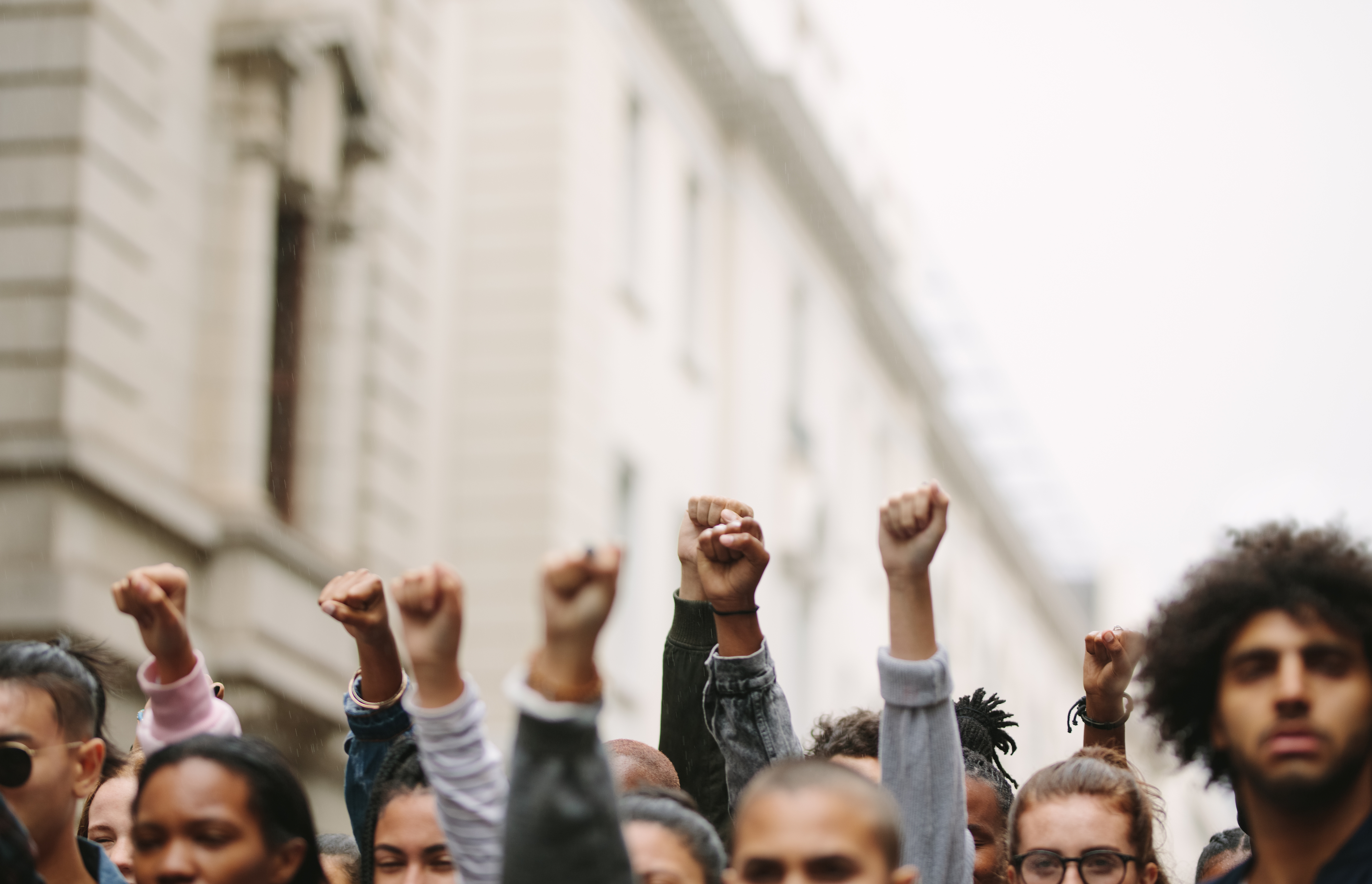 Combatting Radicalization. Arms raised in protest. Group of protestors fists raised up in the air.